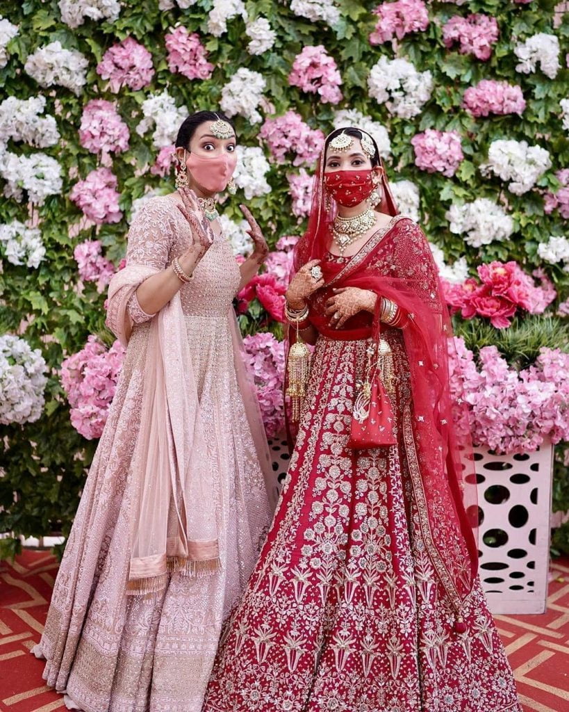 outfit coordinated masks with bride and bridesmaid in pastel and traditional red lehengas