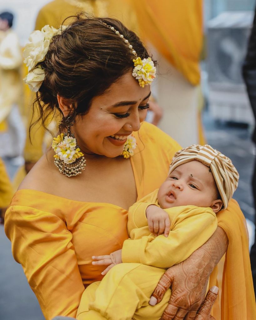 neha holding baby during haldi ceremony with yellow white floral haldi jewellery 