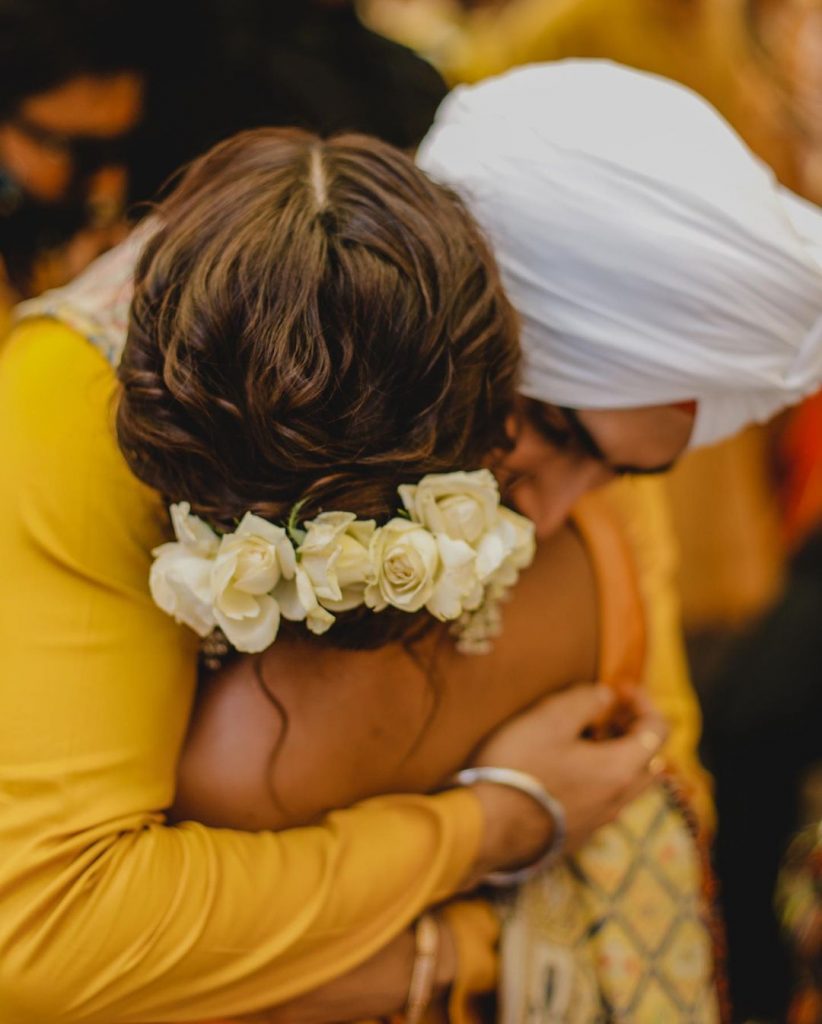 neha with floral hair bun hugging groom rohanpreet